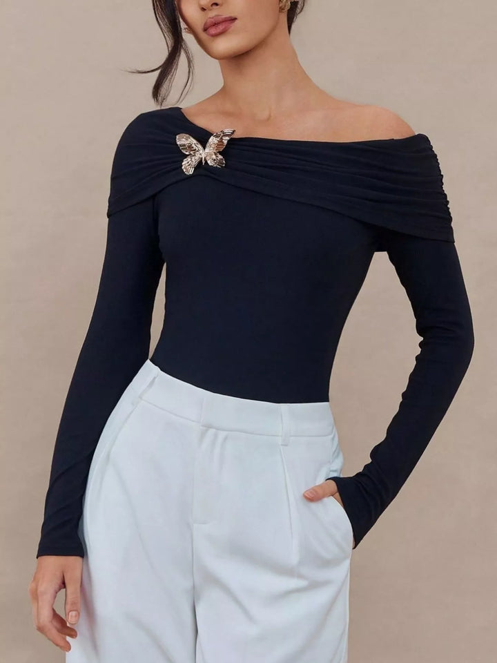 Off-shoulder long sleeve top with gold butterfly brooch