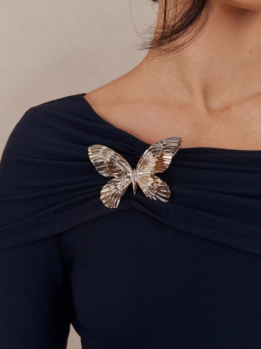 Off-shoulder long sleeve top with gold butterfly brooch