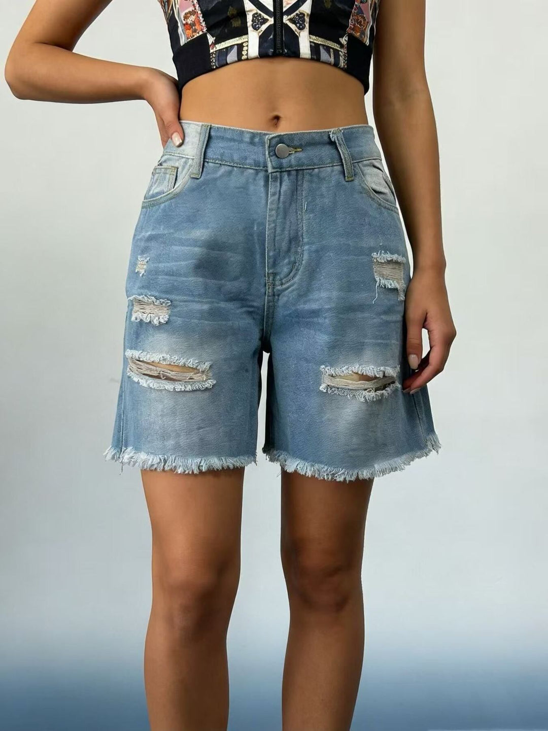Distressed mid-thigh denim shorts with raw frayed hem