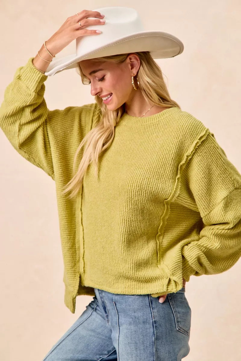 Ribbed boucle knit sweater with exposed seams and uneven hem