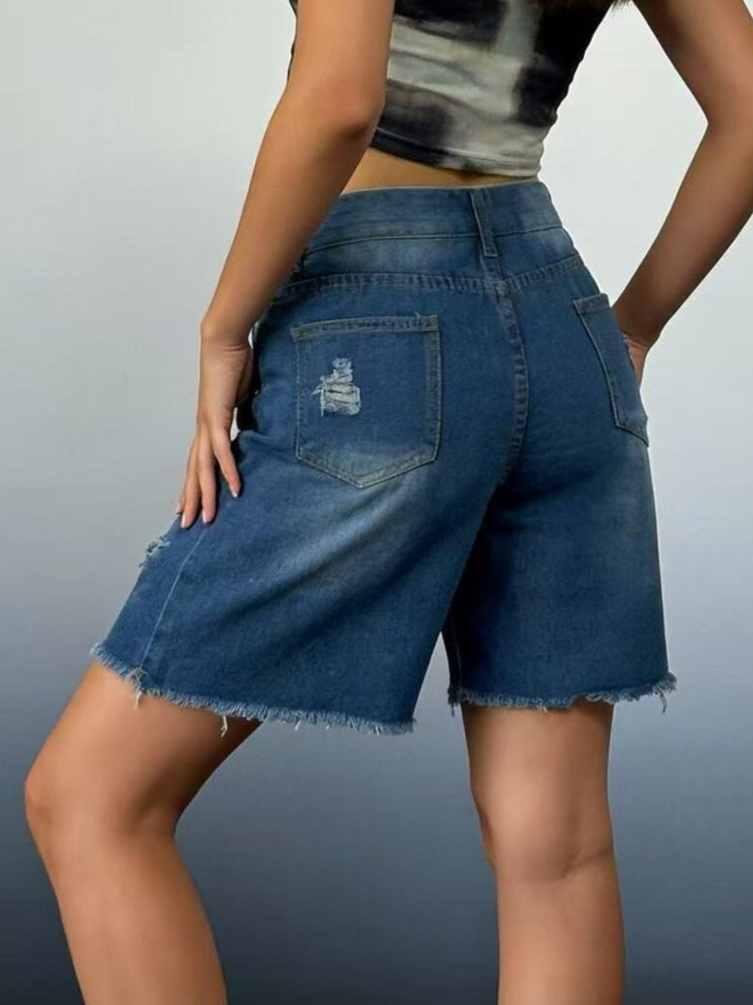 Distressed mid-thigh denim shorts with raw frayed hem
