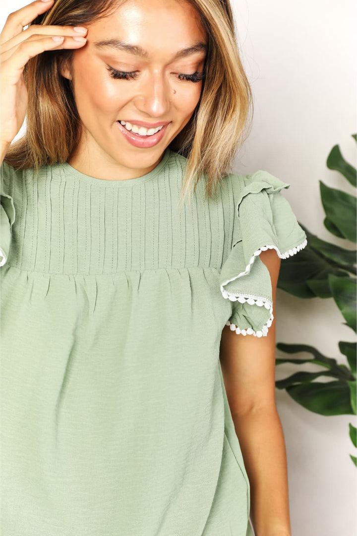 Pintuck yoke flutter sleeve blouse with pom-pom trim