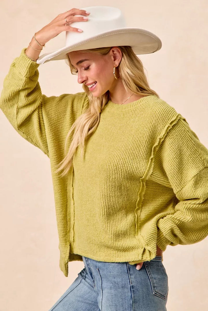 Ribbed boucle knit sweater with exposed seams and uneven hem