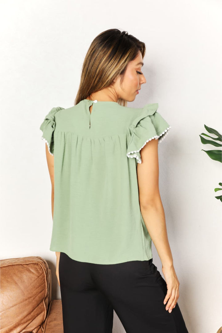 Pintuck yoke flutter sleeve blouse with pom-pom trim