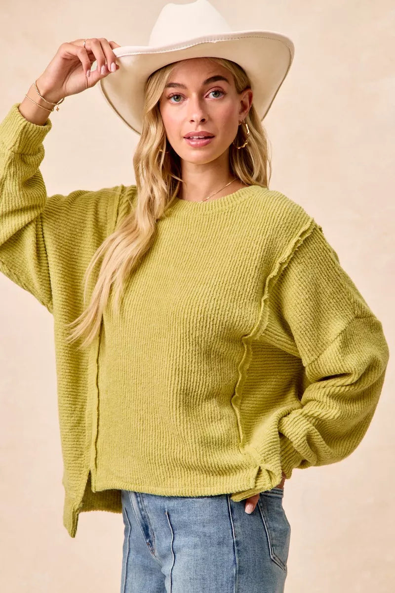 Ribbed boucle knit sweater with exposed seams and uneven hem