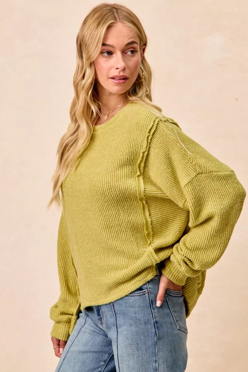 Ribbed boucle knit sweater with exposed seams and uneven hem