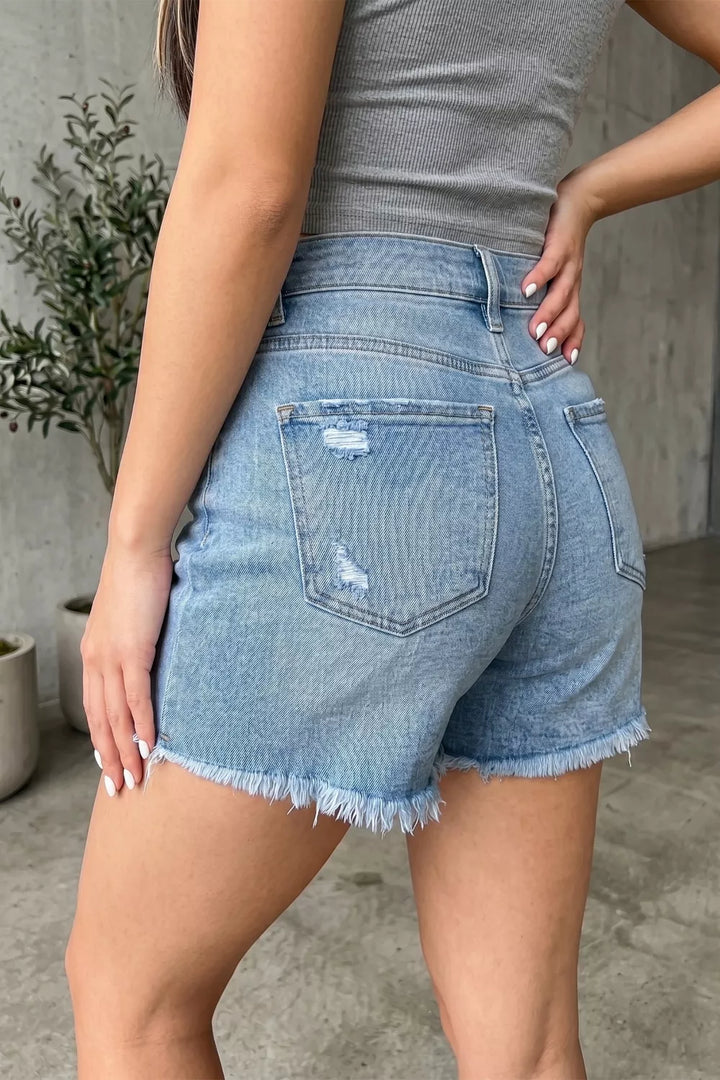 Distressed mid-rise denim shorts with asymmetric raw hem