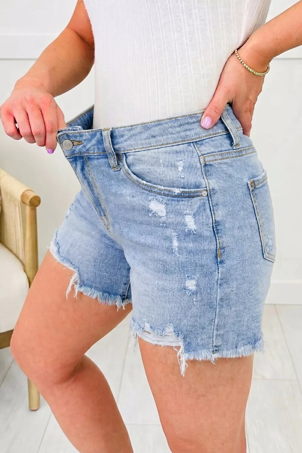 Distressed mid-rise denim shorts with asymmetric raw hem