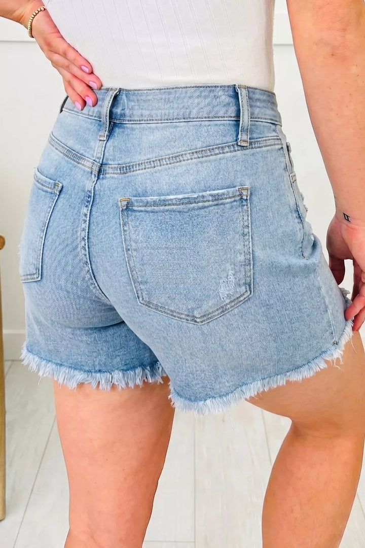 Distressed mid-rise denim shorts with asymmetric raw hem